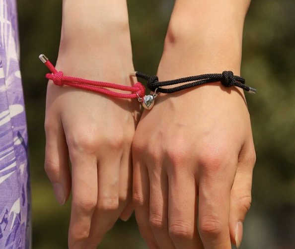 Un couple qui colle ses deux mains pour que leur bracelet respectif forme un coeur